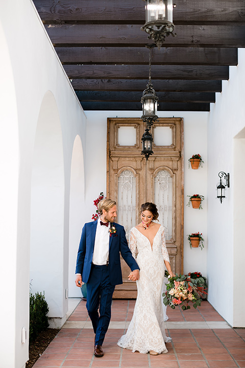  the bride in a lace formfitting gown with sleeves and the groom wore a dark blue suit with a burgundy bow tie