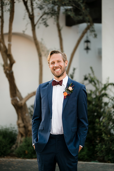 groom in a dark blue suit with a burgundy bow tie