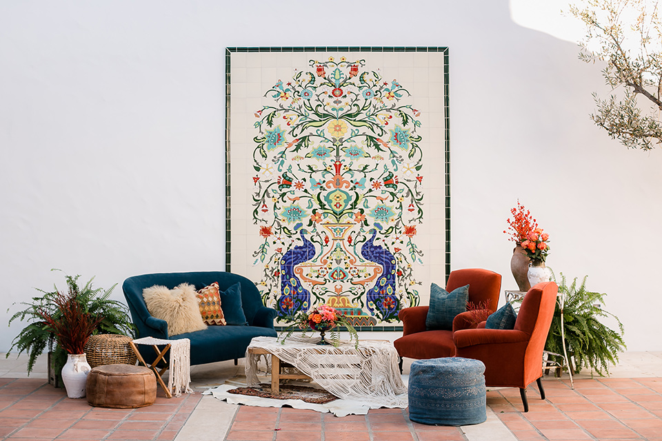  blue velvet couch with white tables and tiled décor on the wall