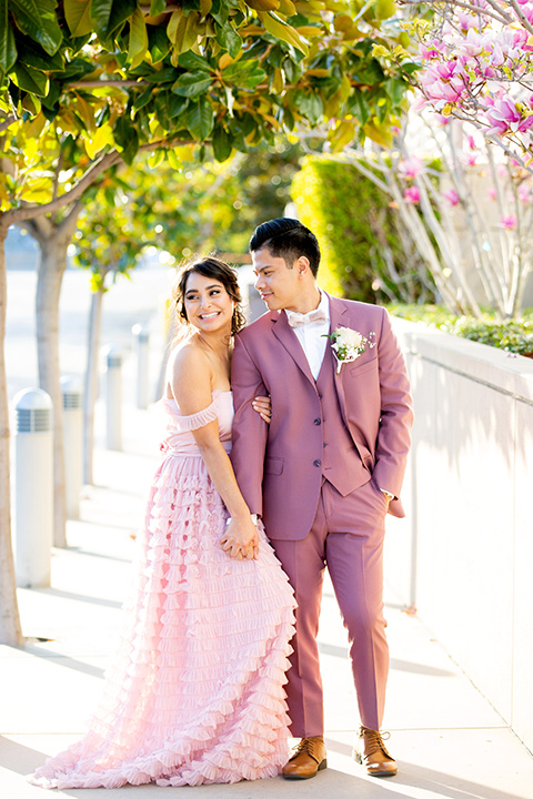  bride in a pink ballgown with ruffles and the groom in a rose pink suit with a pink bow tie