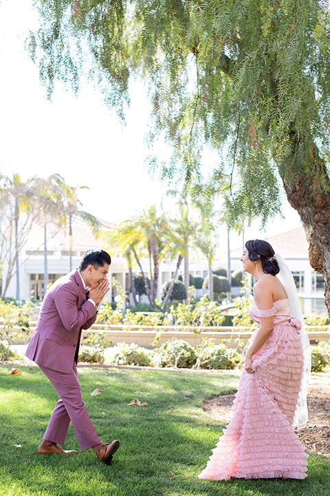  bride in a pink ballgown with ruffles and the groom in a rose pink suit with a pink bow tie