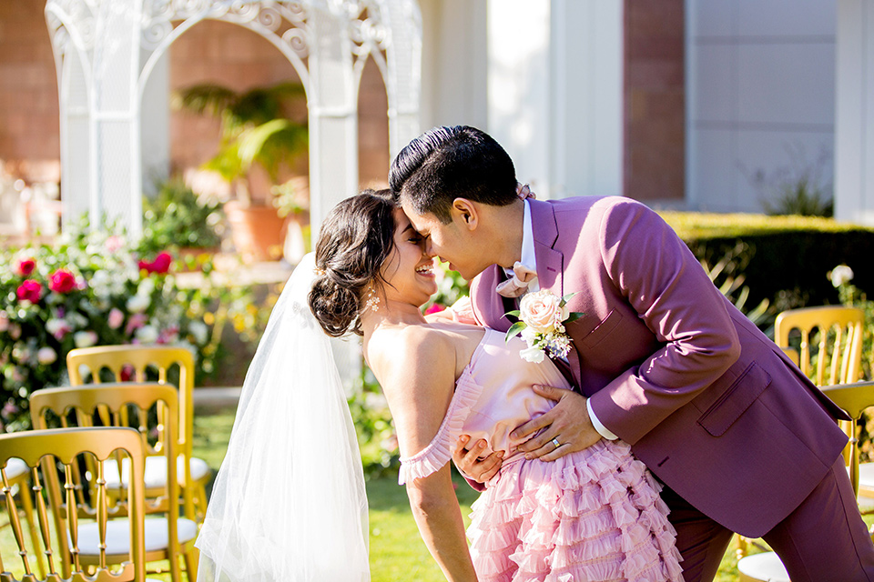  bride in a pink ballgown with ruffles and strapless neckline and the groom in a rose pink suit with a pink bow tie