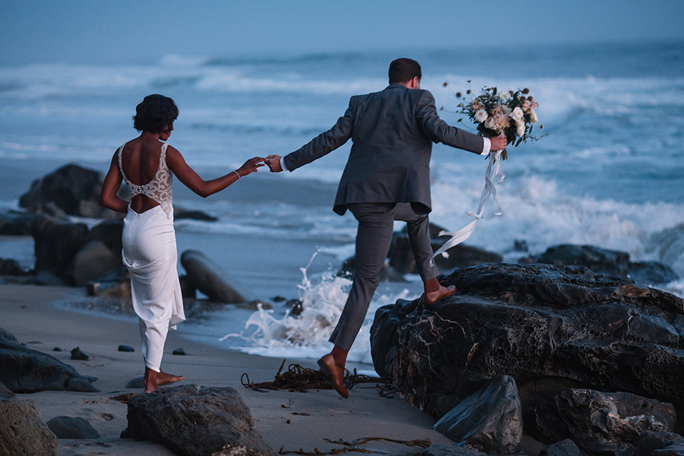  bride and groom jumping on rocks 