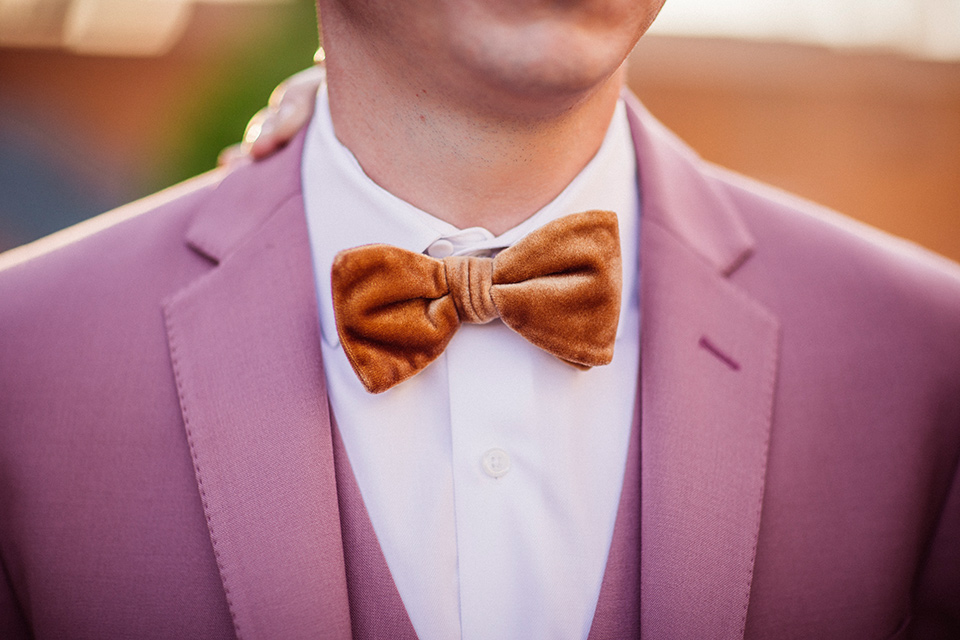 groom in a rose pink suit with a gold velvet bow tie