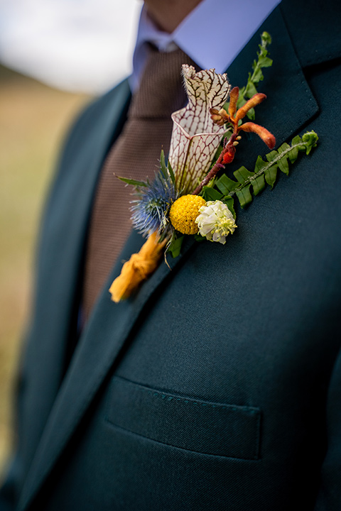  the groom in a dark green suit and brown long tie