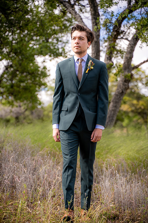  the groom in a dark green suit and brown long tie 