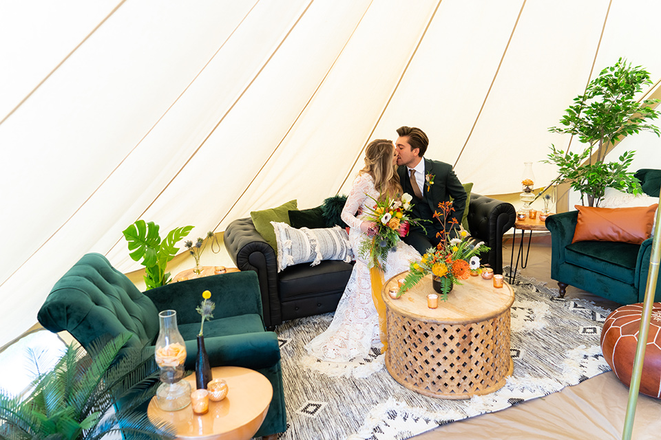  the groom in a dark green suit and brown long tie and bride in a lace gown with long sleeves 