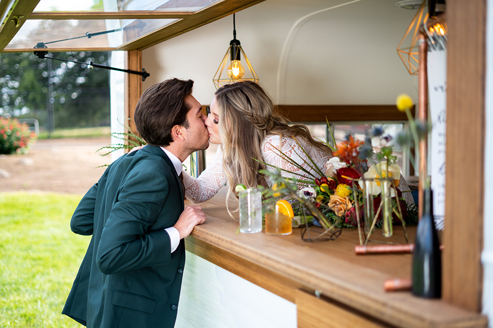  the groom in a dark green suit and brown long tie and bride in a lace gown with long sleeves 