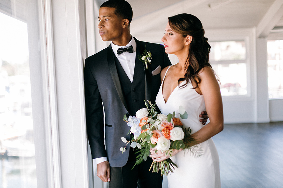  bride in a lace white gown with a long veil and the groom in a navy shawl lapel tuxedo with black bow ties