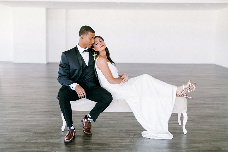  bride in a lace white gown with a long veil and the groom in a navy shawl lapel tuxedo with black bow ties