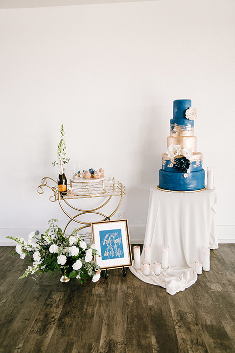  white and blue cake with white table linens and gold decor