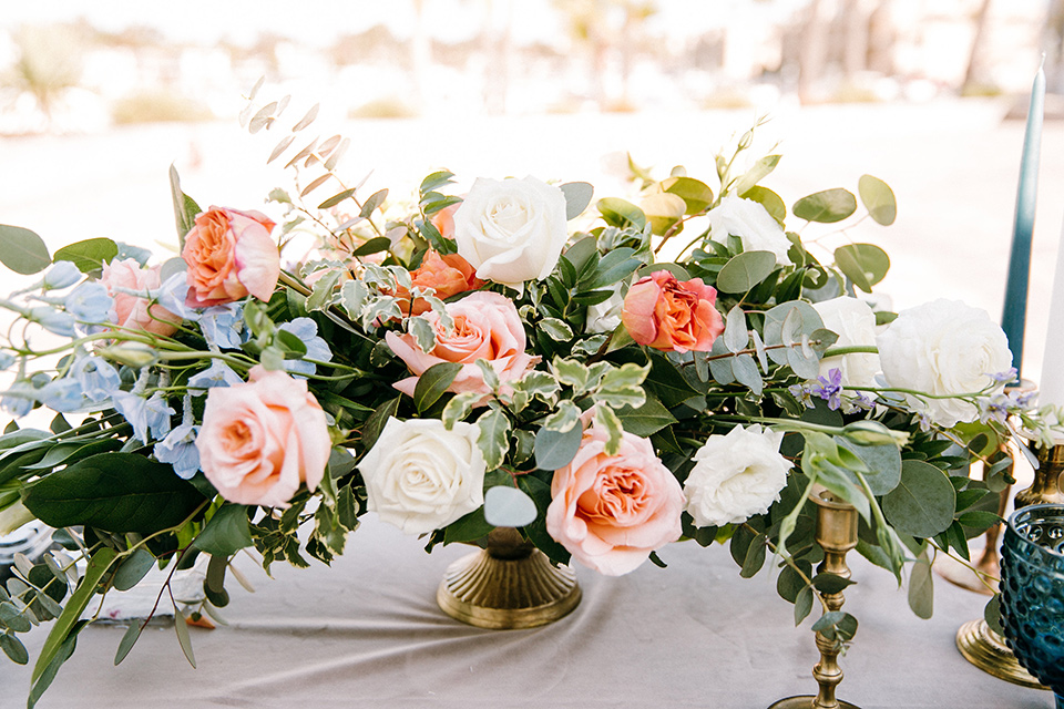  pink and peach colored roses with greenery on the table
