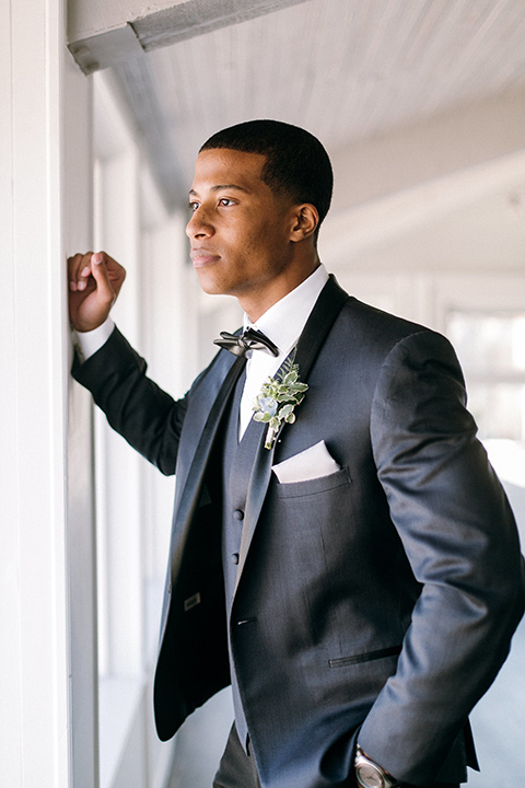  the groom in a navy shawl lapel tuxedo with black bow ties