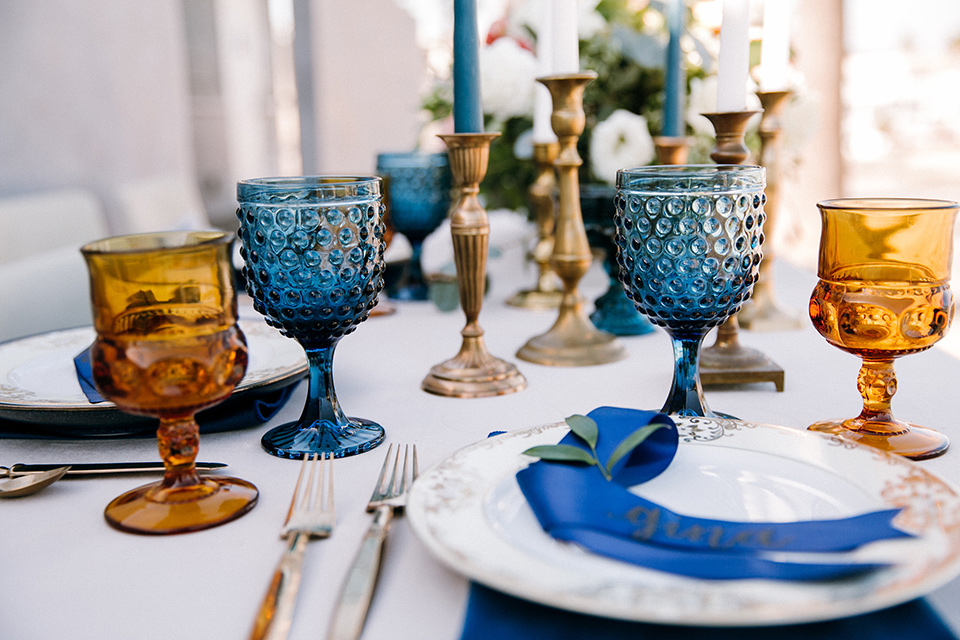  blue and orange décor on a table with white linens and gold flatware