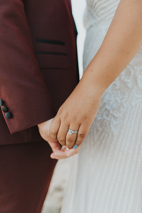  bride in a white lace gown and the groom in a burgundy tuxedo 