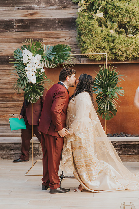  bride in a white lace gown and the groom in a burgundy tuxedo 