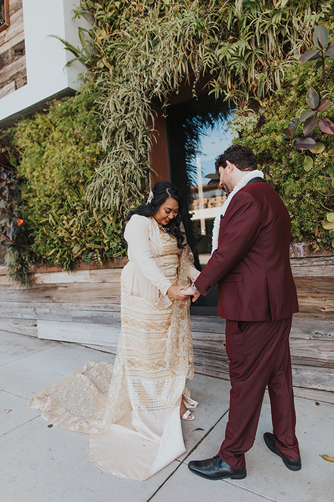  bride in a white lace gown and the groom in a burgundy tuxedo 