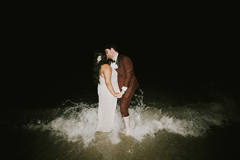  bride in a white lace gown, the groom in a burgundy tuxedo with a black shawl