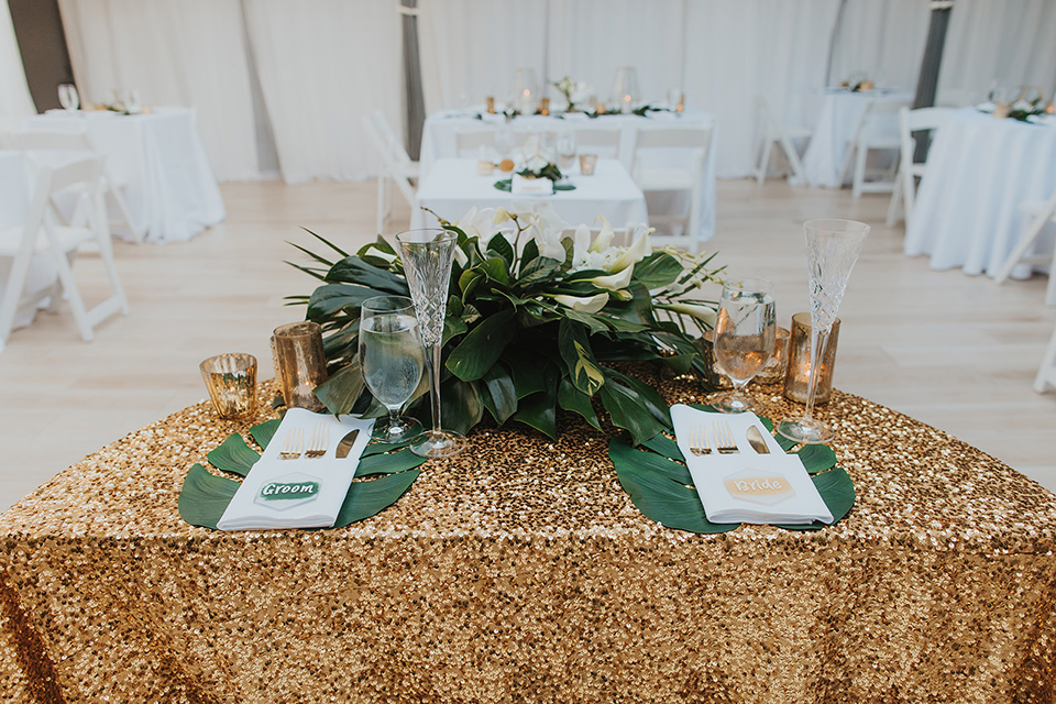  reception tables with gold linens and tropical decor