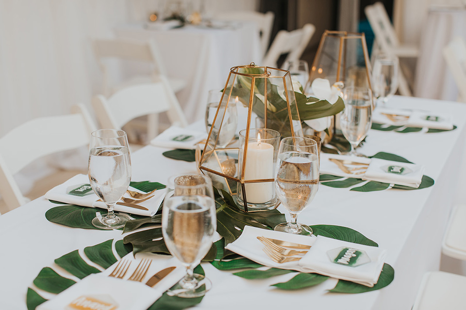  reception tables with gold linens and tropical decor