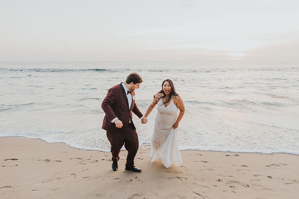  bride in a white lace gown, the groom in a burgundy tuxedo with a black shawl