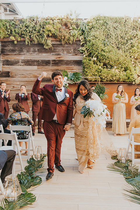  bride in a white lace gown and the groom in a burgundy tuxedo 