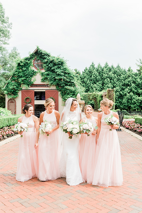  bride in a white lace gown and the groom in a burgundy tuxedo and the bridesmaids in blush toned gowns