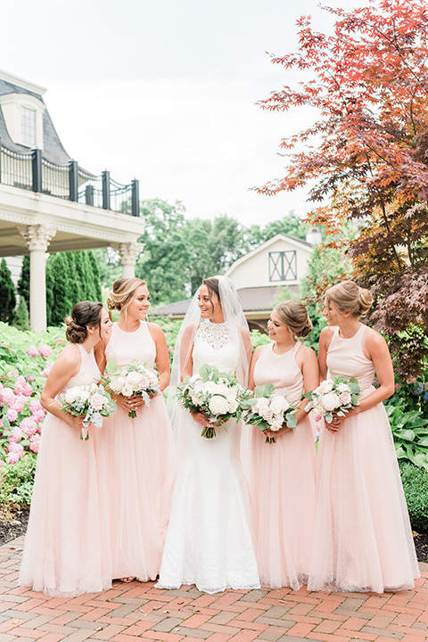  bride in a white modern lace gown with a cathedral veil and bridesmaids in blush toned gowns