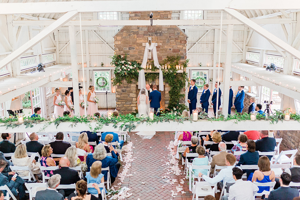  bride in a white modern lace gown with a cathedral veil and the groom in a cobalt blue suit, the bridesmaids in blush pink gown and the groomsmen in cobalt blue suits