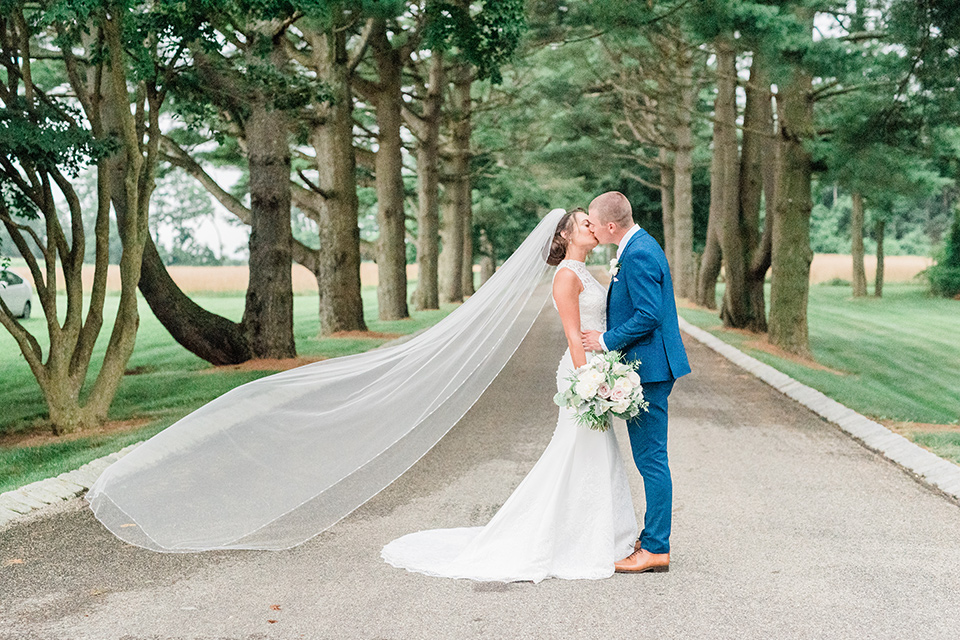  bride in a white modern lace gown with a cathedral veil and the groom in a cobalt blue suit