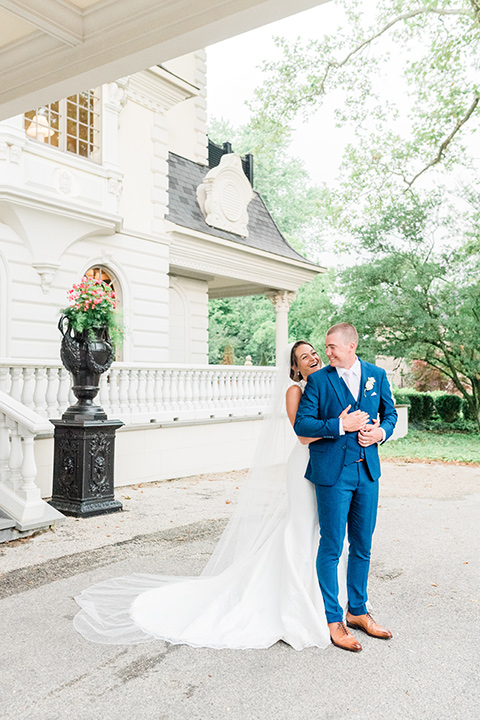  bride in a white lace gown and the groom in a burgundy tuxedo and the bridesmaids in blush toned gowns and the groom in  a cobalt blue suit