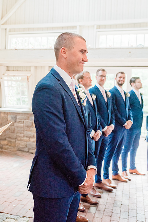  bride in a white lace gown and the groom in a burgundy tuxedo and the bridesmaids in blush toned gowns