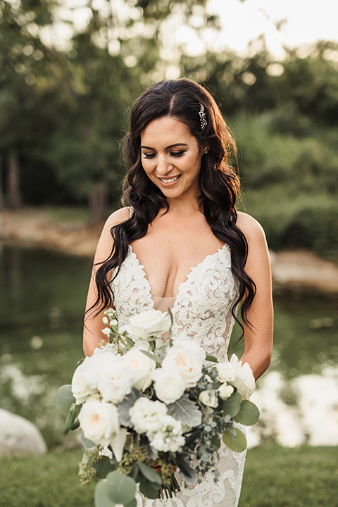  bride in a two-piece gown with a cream top and blue tulle skirt, and the groom in a navy notch lapel suit with a navy tie – under the trees