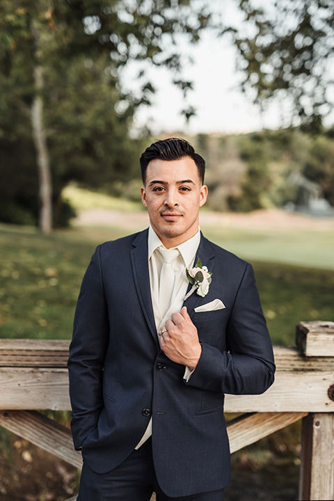  groom in a navy suit with brown shoes and white long tie