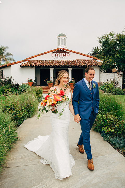  bride in a formfitting lace gown and the groom in a blue suit 