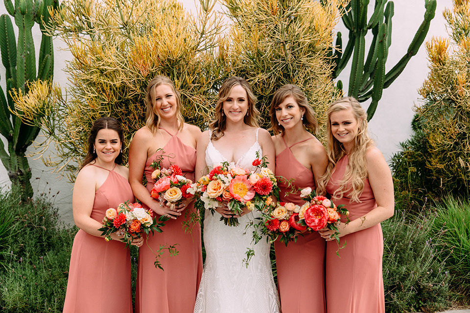  bride in a formfitting lace gown the bridesmaids in desert sunset colored gowns 