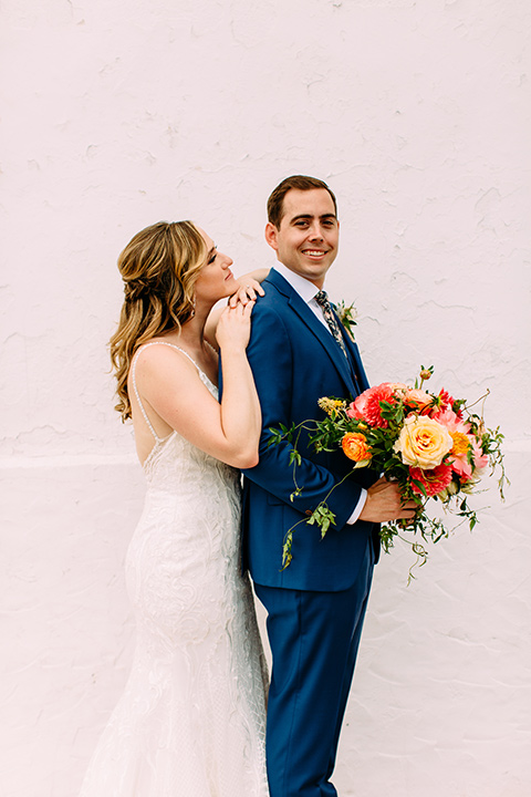  bride in a formfitting lace gown and the groom in a blue suit 