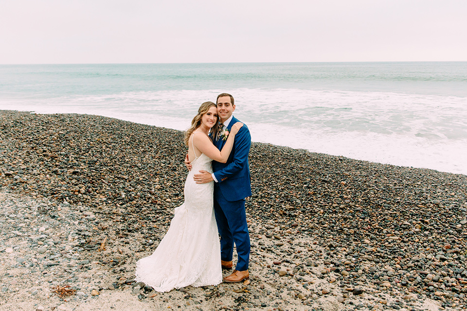  bride in a formfitting lace gown and the groom in a blue suit 