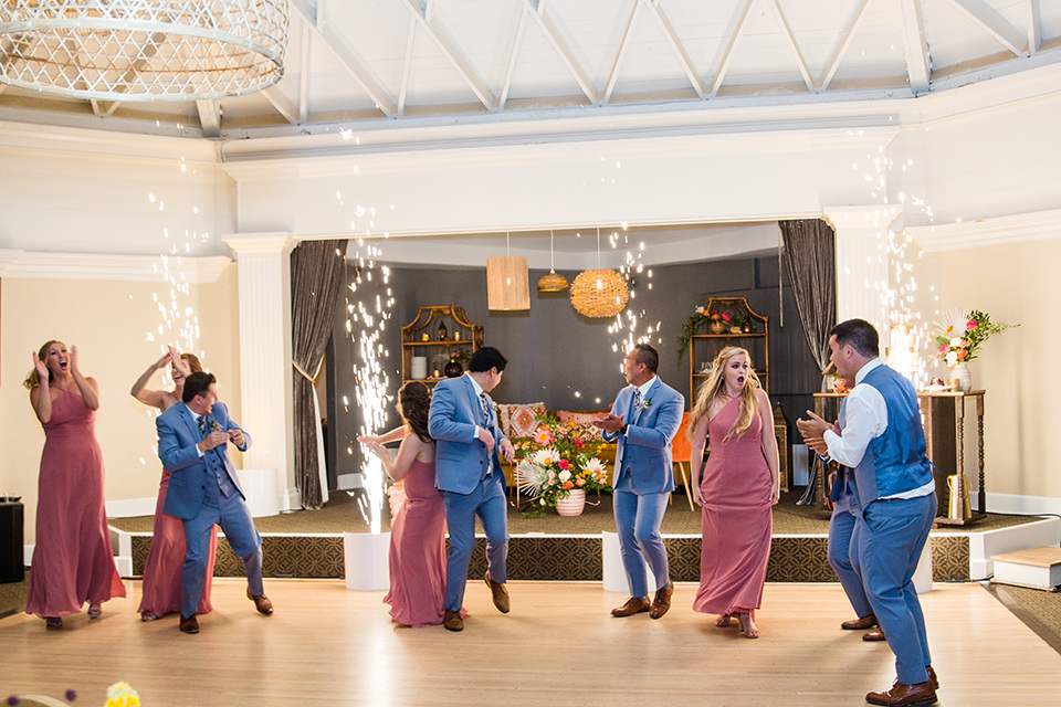  bride in a formfitting lace gown and the groom in a blue suit everyone dancing