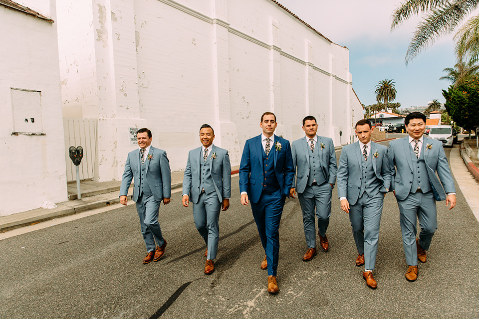  the groom in a blue suit and the groomsmen in light blue suits
