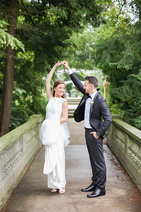  groom in a black tuxedo with a black bow tie and accessories bride in a white gown with a high neckline and veil 