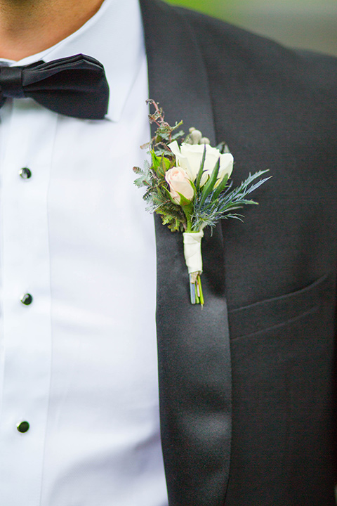 groom in a black tuxedo with a black bow tie and accessories