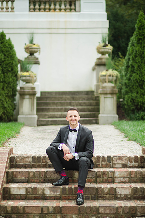 groom in a black tuxedo with a black bow tie and accessories