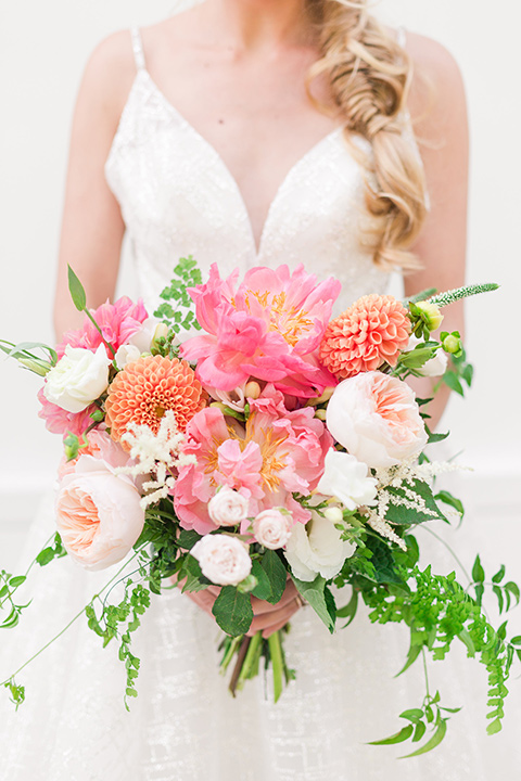  bride in a white lace ballgown with a pink bouquet and hair in a braid 