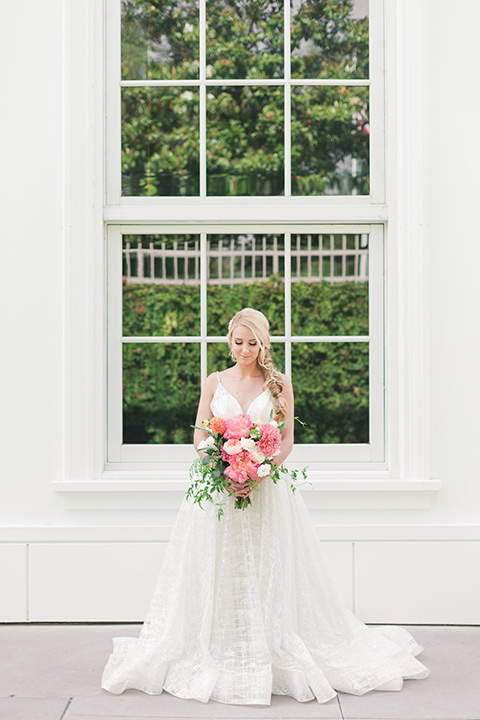  bride in a white lace ballgown with a pink bouquet and hair in a braid 