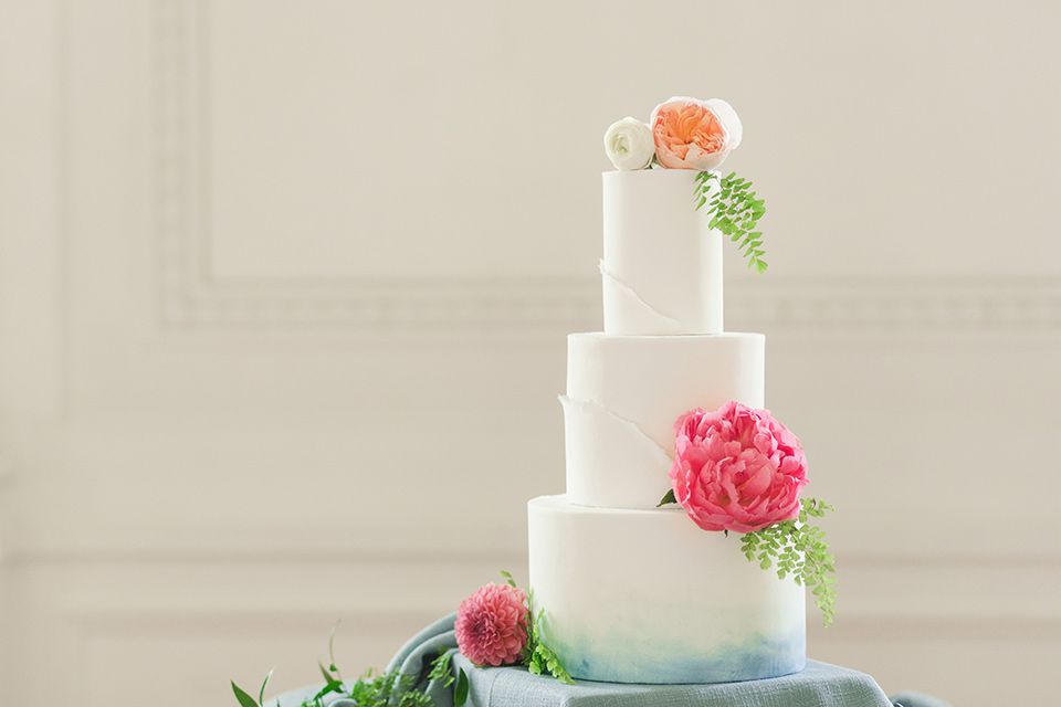 white tiered cake with bright pink and green flowers