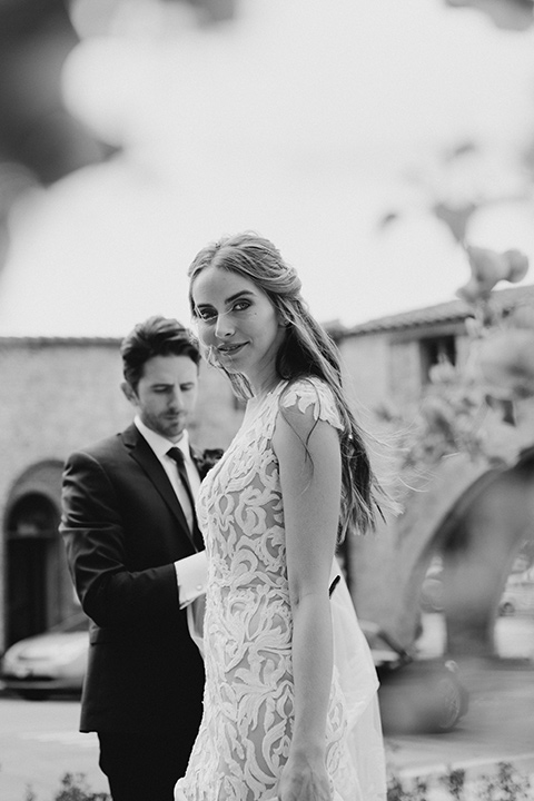  bride in a white lace gown with an illusion neckline and flowing train and the groom in a navy notch lapel suit with a deep teal long tie 