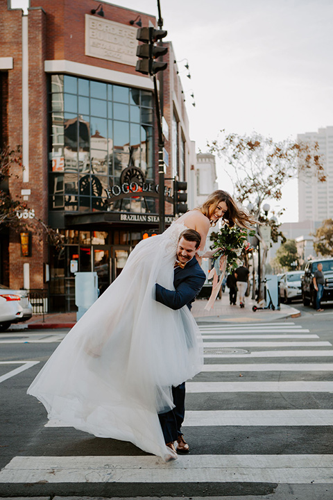  bride in a full skirt gown with an off the shoulder detail and the groom in dark blue suit and bow tie