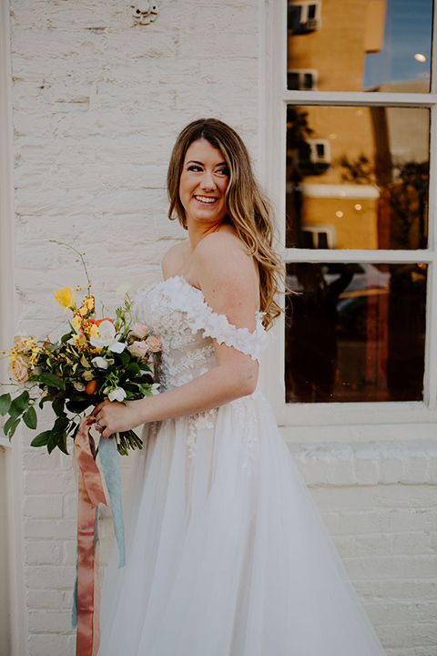  bride in a full skirt gown with an off the shoulder detail 