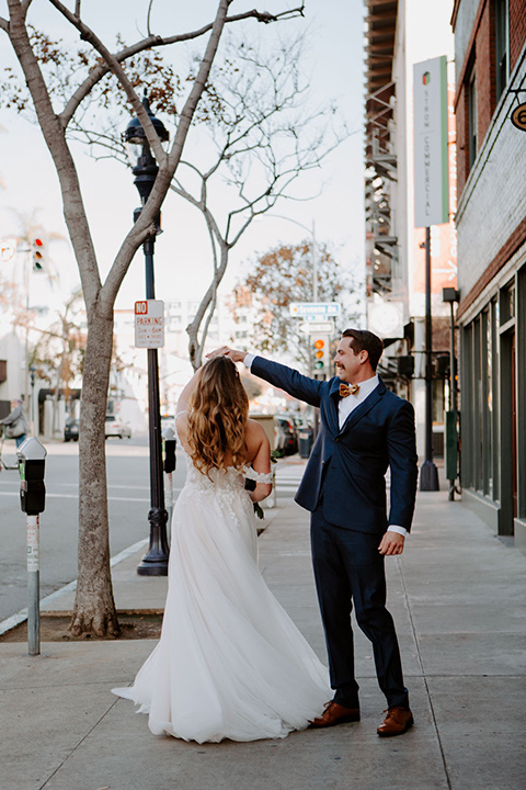  bride in a full skirt gown with an off the shoulder detail and the groom in dark blue suit and bow tie